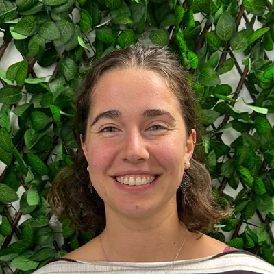 Chiropractor Karolina Smiling In Front Of Leaf Wall